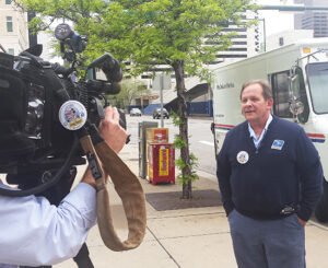 A TV news crew interviews Denver Letter Carrier Jeff Frey, a food drive coordinator.
