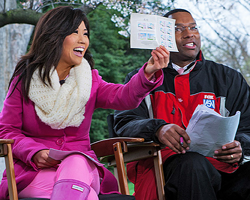 Anchors Annie Yu and Wisdom Martin show the stamps on TV.