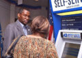 Chicago District Acting Marketing Manager Michael Perry helps a customer at the Cardiss Collins Postal Store, which is open until midnight on weekdays.