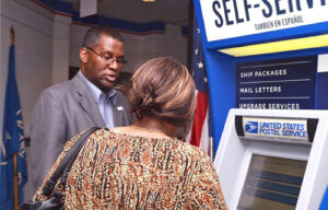 Chicago District Acting Marketing Manager Michael Perry helps a customer at the Cardiss Collins Postal Store, which is open until midnight on weekdays.