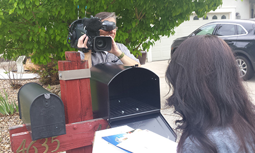 A news crew films a customer testing a new mailbox.