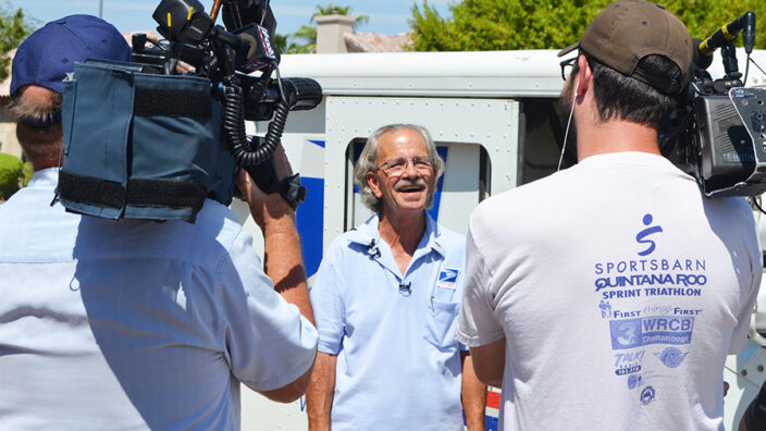 Glendale, AZ, Letter Carrier Michael Raymer is interviewed by local TV news crews.