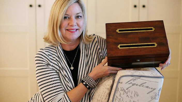 Dallie Clark — a humanities professor at Collin College in Plano, TX — holds an antique letter box.