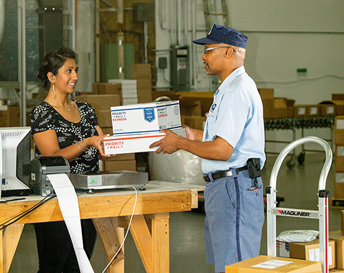 A letter carrier delivers packages to a customer.