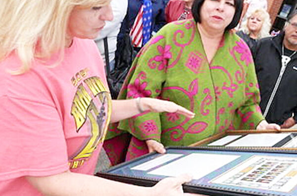 Oak Hill, OH, Post Office Officer in Charge Jill Walters presents stamps to Ann Leavenworth, niece of Honor recipient Sgt. Donald Long.