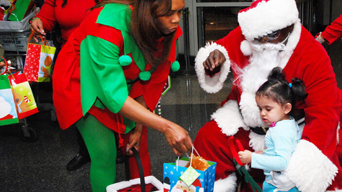 Chicago Acting Postmaster Tangela Bush and Santa Claus (Mechanic Eddie Spearman) pass out gift bags at a recent Operation Santa event.