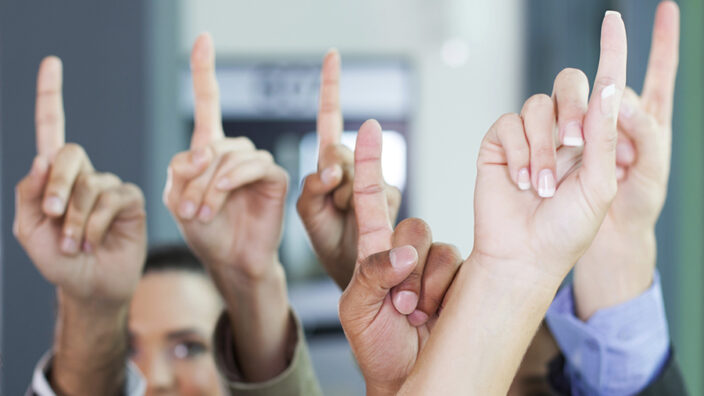 A group of people holding up their fingers to signify that they're number 1.