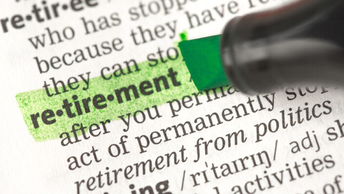 Someone highlighting the word: retirement on a page from the dictionary.