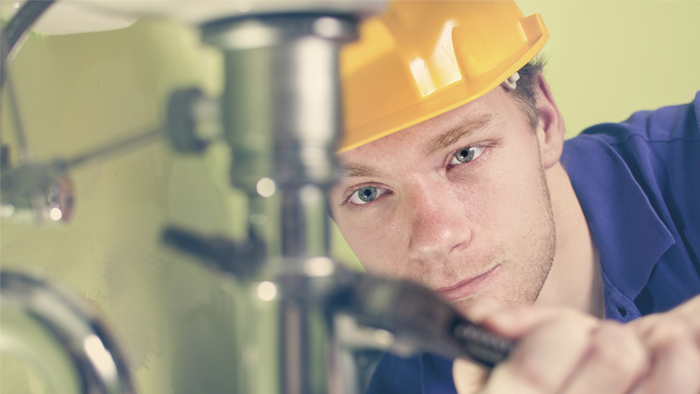 Someone in a hard hat tightening a pipe.