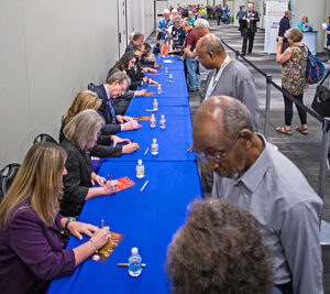 Participants autograph programs for stamp collectors at the show, which is being held in New York City.
