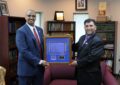 Detroit Postmaster Derron Bray and Dearborn Heights, MI, Postmaster Yousef Abusalah hold framed stamp artwork.