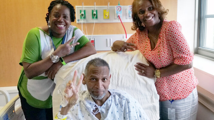 USPS Headquarters Maintenance Supervisor Gwendolyn Harvey and Purchasing and Supply Management Training Coordinator Alice Parks visit Maintenance Operations Manager Derrick Coleman in the hospital.