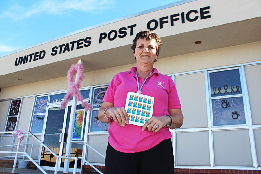 Carl Junction, MO, Postmaster Sharon Clark displays Breast Cancer Research stamp sheet outside the Post Office last year.
