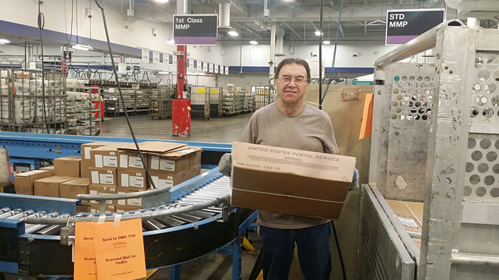 Sioux Falls, SD, Mail Processing Clerk carries a tray of the retailer’s letters.