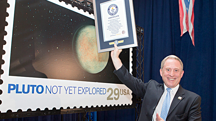 New Horizons Principal Investigator Alan Stern holds one of the Guinness world record certificates presented to the Postal Service and NASA July 19.