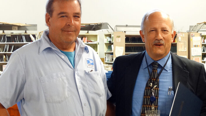 Buffalo, NY, Letter Carrier John Scive, left, with Postmaster Thomas Szklarz at a ceremony recognizing Scive’s heroism.