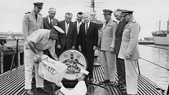 Postmaster General Arthur Summerfield, fourth from left, postal officials and U.S. Navy personnel watch the loading of missile mail into the Navy submarine USS Barbero.