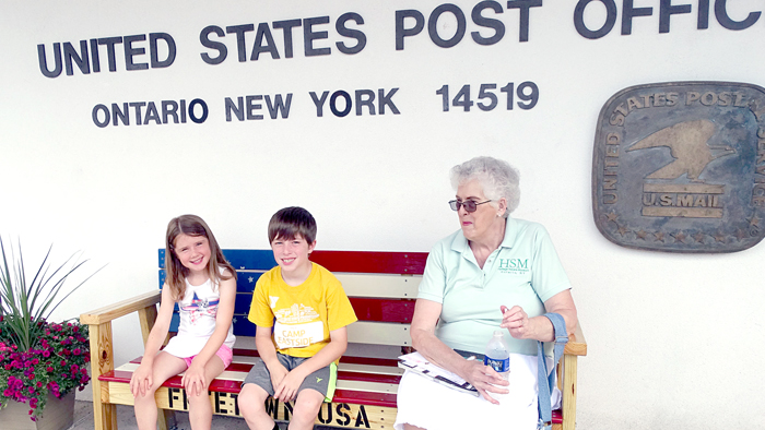 Ontario Post Office customers enjoy the new bench, which was hand-crafted by Custodian Phil Tallinger.