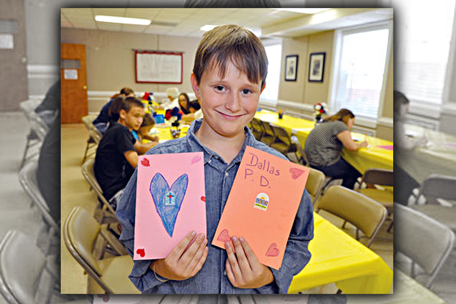 Gavin Mayo holds two the cards and letters created for his campaign to mail encouraging notes to the Dallas Police Department. Image: Carteret County News-Times