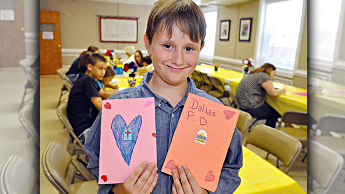 Gavin Mayo holds two the cards and letters created for his campaign to mail encouraging notes to the Dallas Police Department. Image: Carteret County News-Times