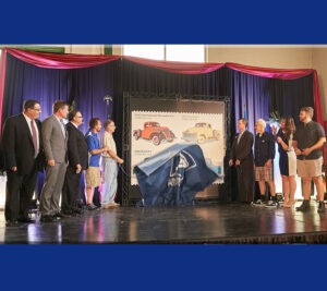 Unveiling the stamp are, from left, Albany District Marketing Manager Frank Raso, Cottrell, pastor George Miller III, car show officials Rob O’Connor and Bob O’Connor, Williamson, stamp illustrator Chris Lyons, broadcaster Lacy Leonardi and Rayo.