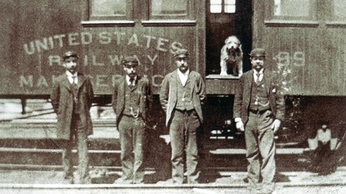 Owney stands inside a train near his railway mail clerk friends. Image: National Postal Museum