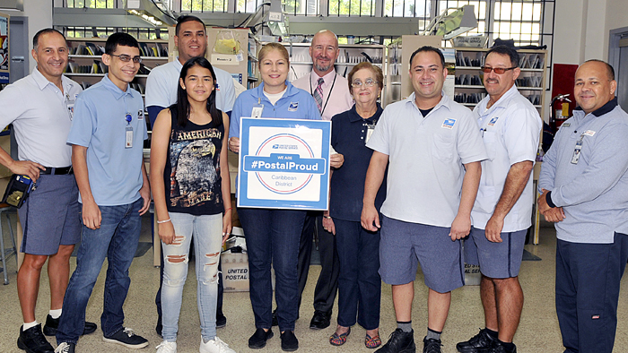 Adrianna Diaz, fourth from left, expresses her postal pride alongside the Utauado, PR, Post Office team, including Postmaster Carlos Roman, sixth from left.