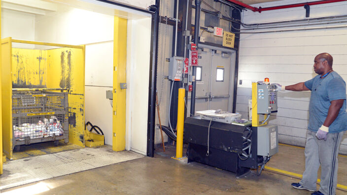 Ken Bell, a custodian at the Chicago Network Distribution Center, feeds cardboard into a baler that prepares the material for transport to a recycling center.