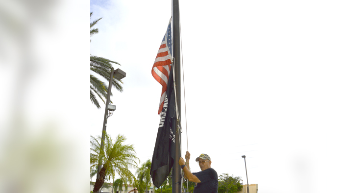 Miami Custodian Lazaro Julve raises the U.S. and POW-MIA flags in front of the Miami General Mail Facility recently.