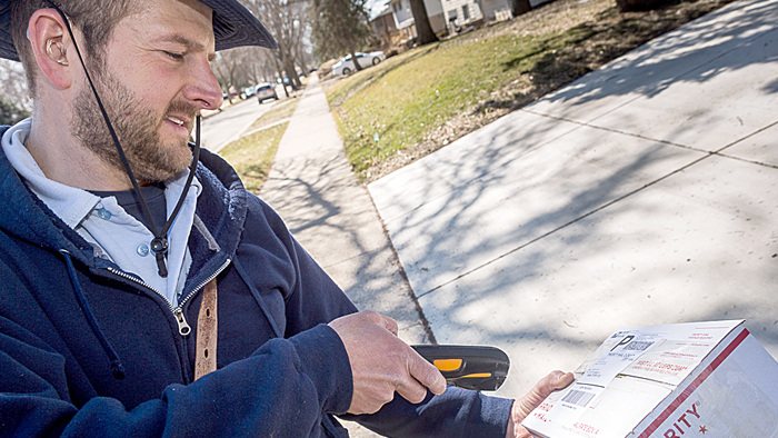 Madison, WI, Letter Carrier Jim Haasch scans a package before delivering it earlier this year. Households received 3.8 billion packages during fiscal 2015, new research shows.