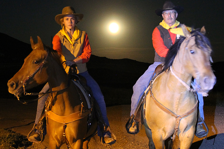 Elena Heer (L), daughter of Guernsey, WY, Clerk Jane Heer and Guernsey Postmaster Curt Artery (R) saddled up under the light of a full moon during a recent Pony Express re-enactment ride.
