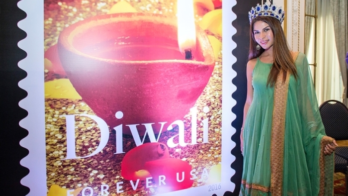 A participant at the Oct. 5 dedication ceremony stands near an image of the Diwali stamp.