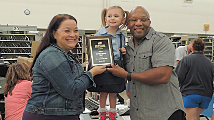 Jennifer Kraft and her daughter, Sophia, and husband, Kory, show off Sophia’s “honorary letter carrier” plaque last week. Image: Courier-Post