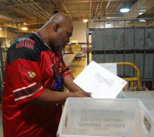 Monty Trabue, a mail handler at the Louisville, KY, Processing and Distribution Center, checks a tub for Election Mail earlier this year.