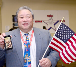 Peter Wong, a Marine Corps’ retired sergeant and the customer services manager at the Jamaica, NY, station, displays his patriotic spirit at a USPS ceremony.