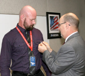 Southern Area VP Shaun Mossman, right, an Army veteran, places a lapel pin on Operations Analyst Chris Farlow at a ceremony in Dallas.
