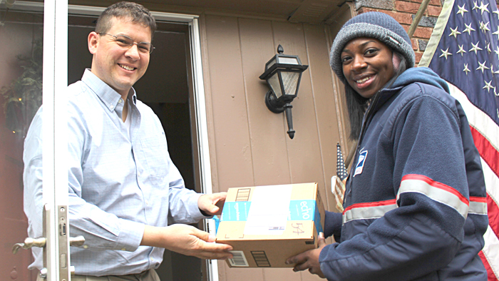 Micah Taylor receives a recent holiday package delivery from Indianapolis City Carrier Assistant Tierra Jackson.