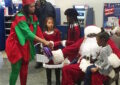 Chicago Postmaster Tangela Bush and Santa Claus — a.k.a. Mechanic Eddie Spearman — hand out gifts and welcome children at Chicago District’s Operation Santa kickoff.