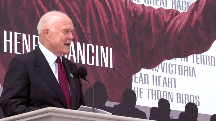 John Glenn helps the Postal Service unveil the Henry Mancini stamp in 2004.