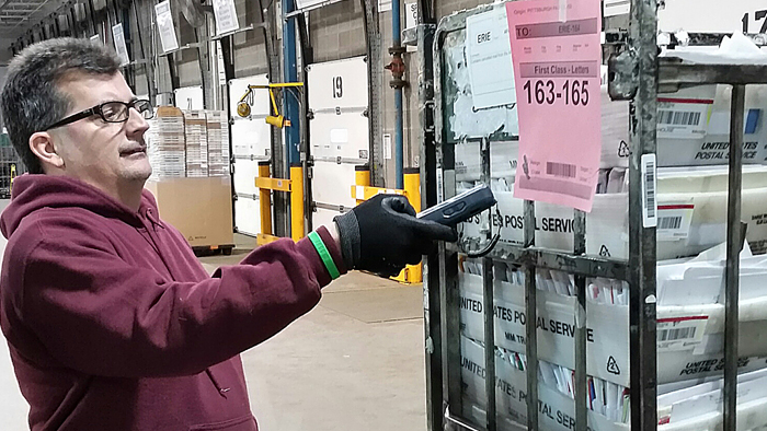 Mail Handler Phil Cassano uses a surface visibility device to scan a container label at the Erie, PA, Processing and Distribution Center.