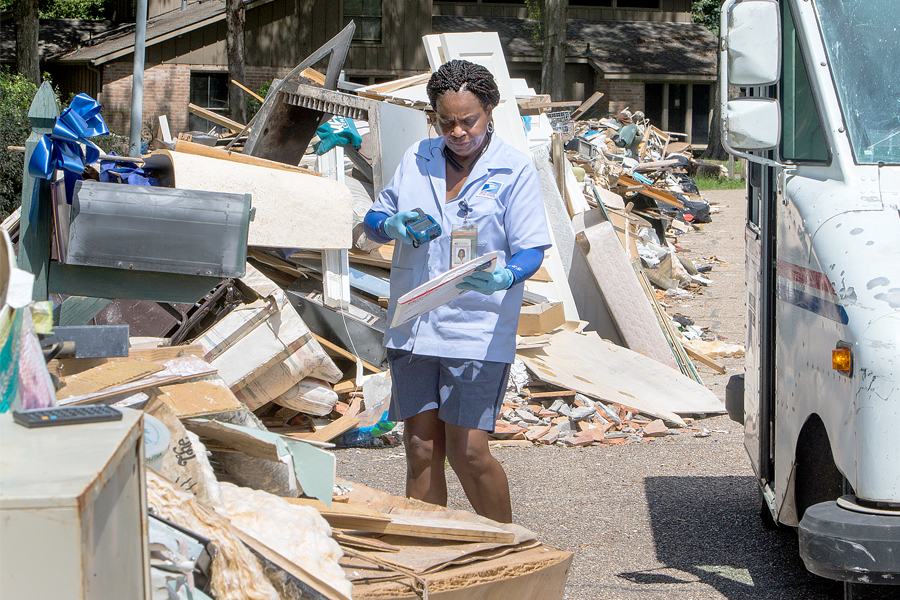Baton Rouge, LA, Letter Carrier Bezeit Miles delivers mail following an August flood.