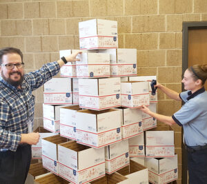 Customer Services Supervisor Joe Rann and Chelsea Winters, a postal support employee, arrange Priority Mail boxes into a festive formation at the Lansing, MI, Main Post Office.