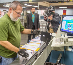 A TV news crew records Clerk Dale Dick working at the Madison, WI, Processing and Distribution Center.