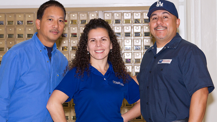 Two men and one woman pose in front of boxes