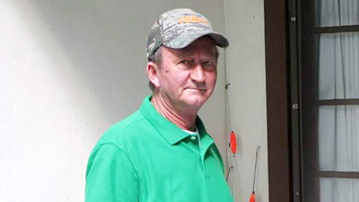 Rural Carrier Roger Burnette wearing a green shirt and baseball hat