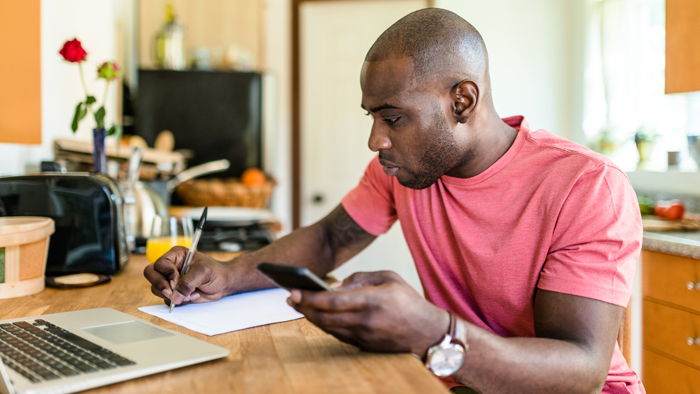 Man holding calculator and writing on sheet of paper