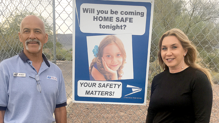 USPS employees stand next to poster