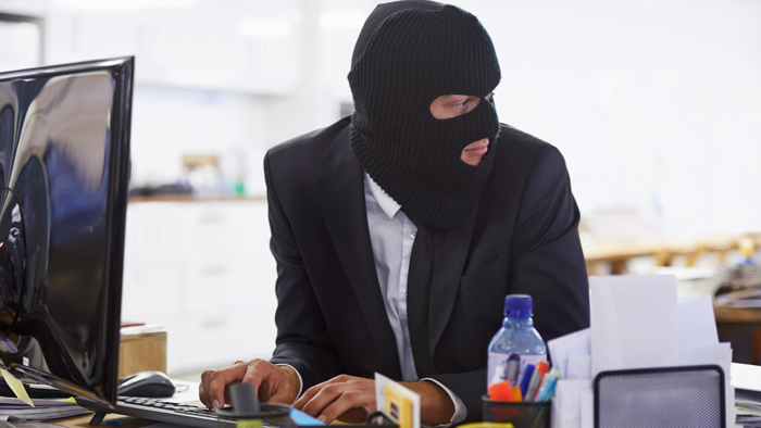 Man in mask types at computer