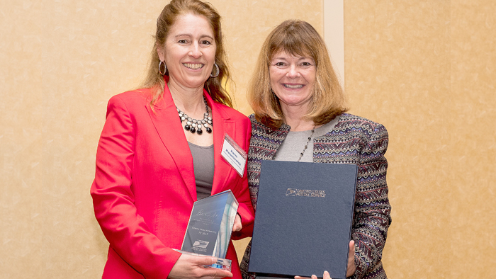 Two USPS employees holding award