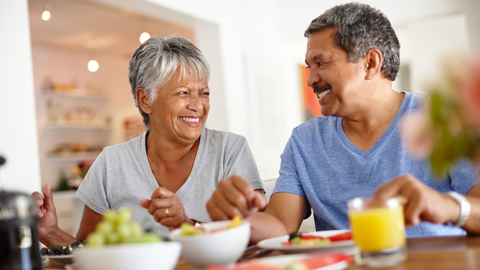 Older African American couple smile at each other over breakfast